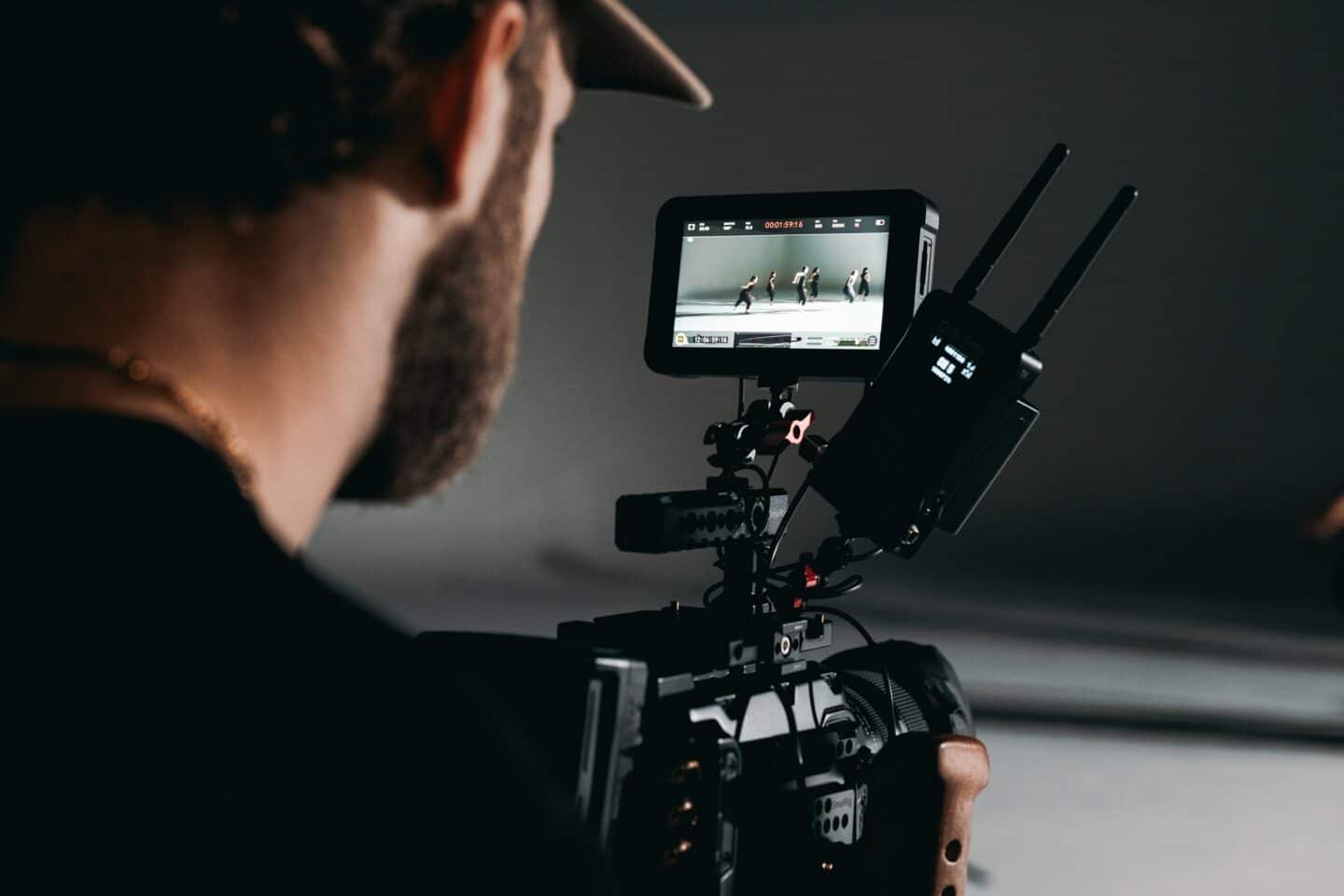 man with beard behind video camera Videography | Wooshii